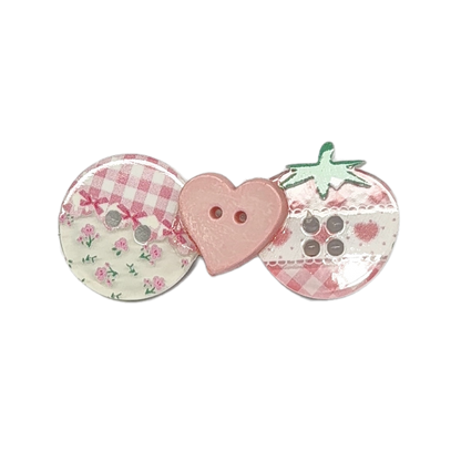 Three decorative buttons arranged side by side on a plain white background: a round button with pink gingham and floral print, a pink heart-shaped button with two holes, and a strawberry-shaped button with green leaves and a pink gingham pattern.